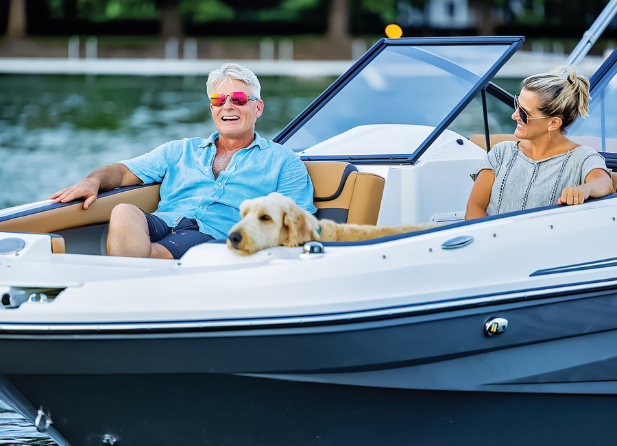 Walter smiling with his dog on the boat and his wife next to him