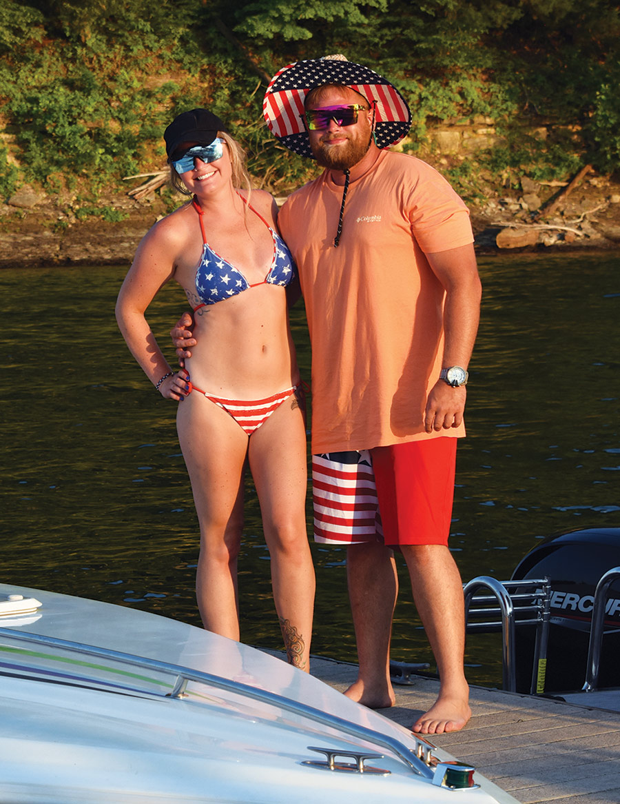 couple in American flag bathing suits smiling together on boat