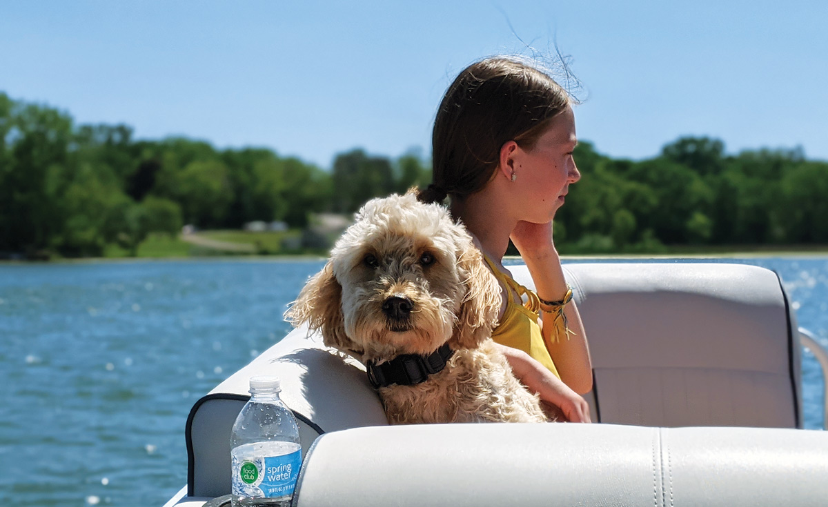 young girl and dog sitting on a boat