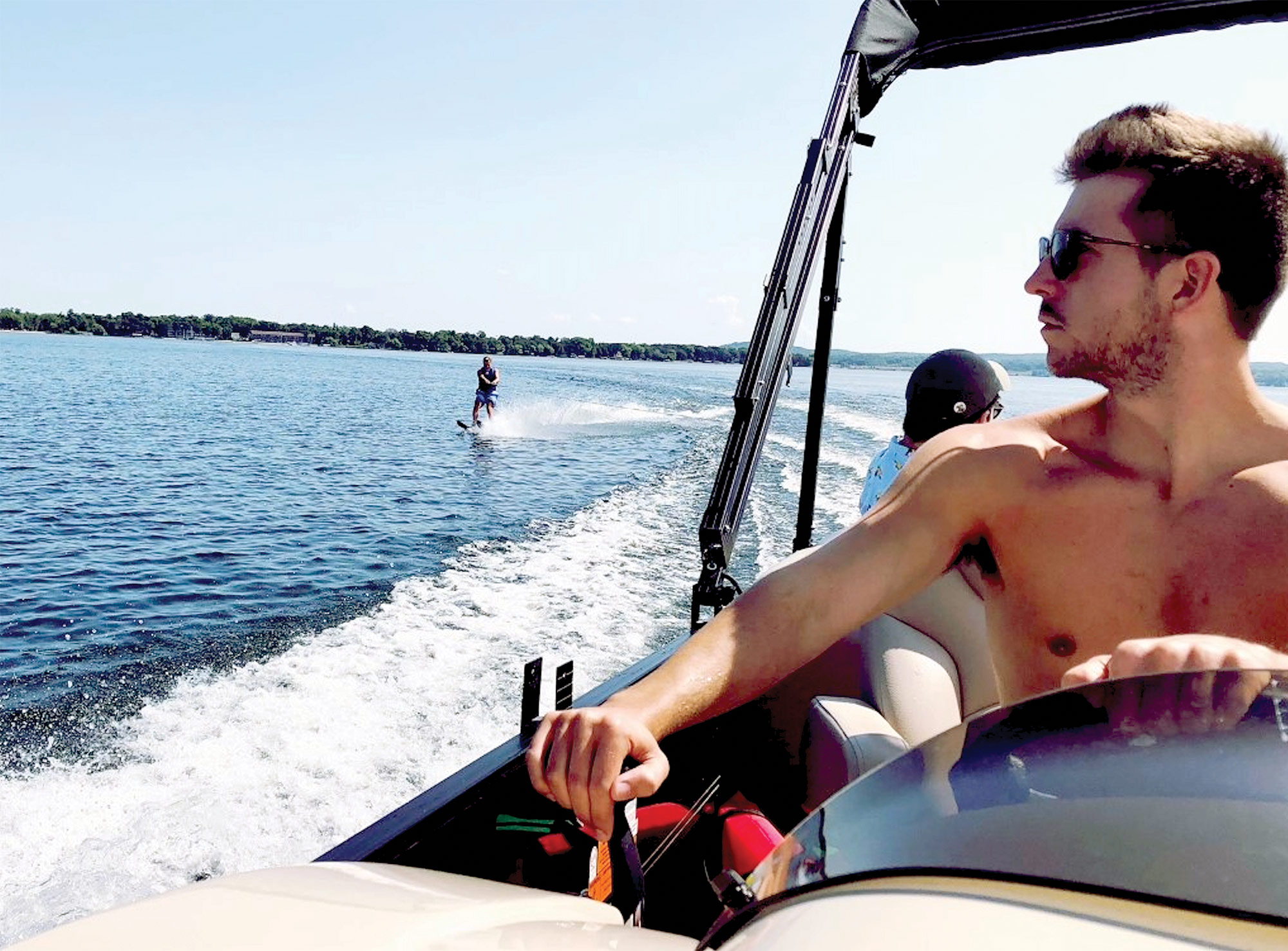 man driving boat with water skiier in the water