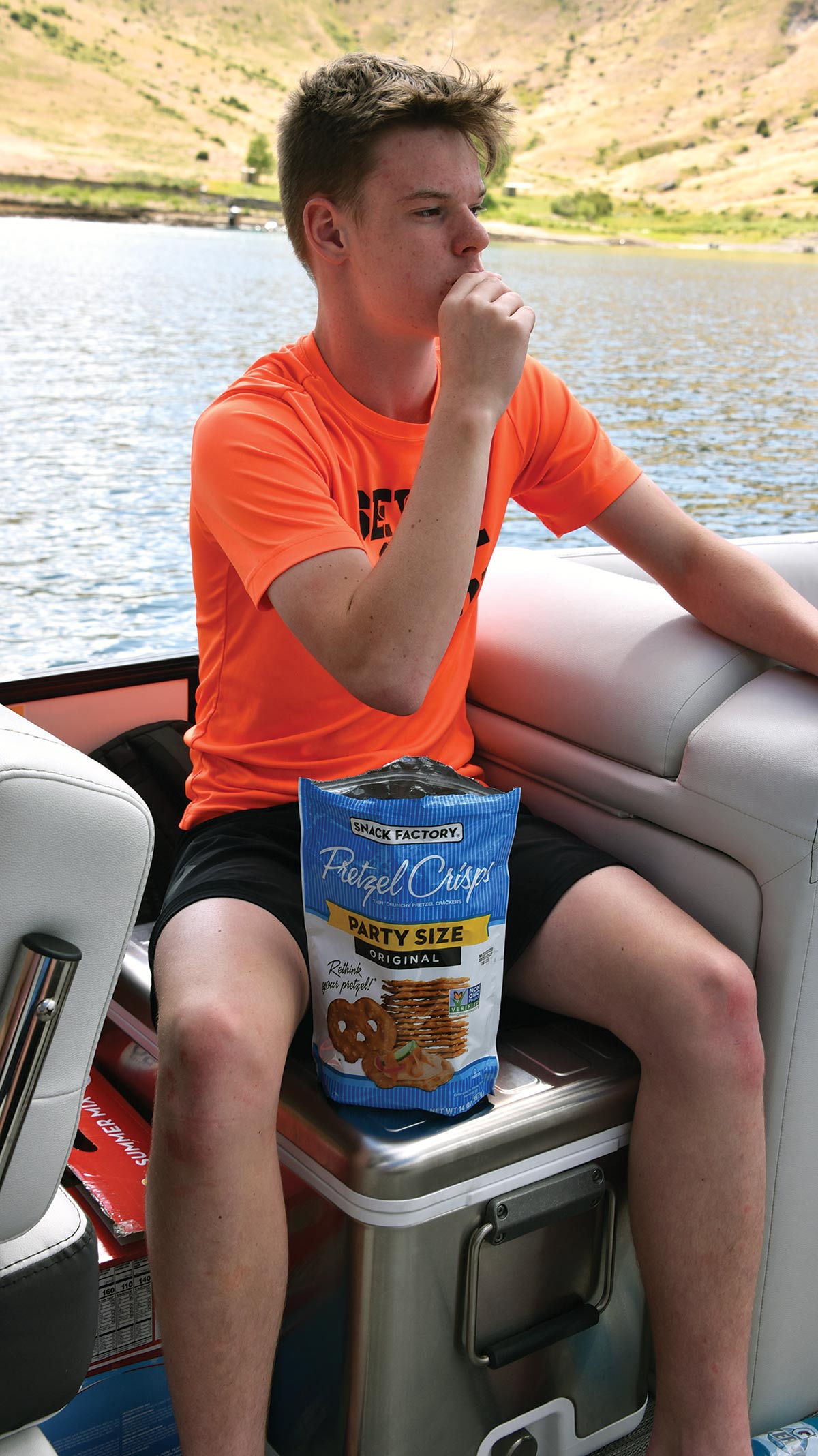 teen boy eating pretzels on boat