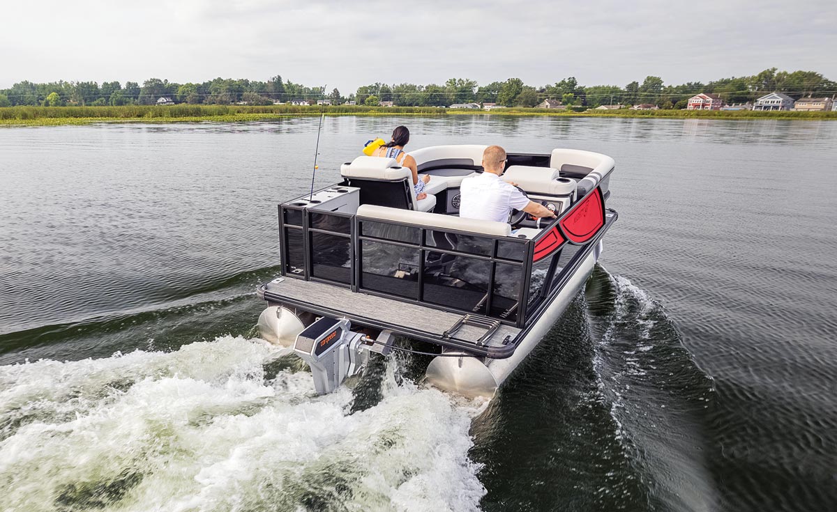 An electric propeled pontoon boat with a young family exploring an open body of water on a grey day