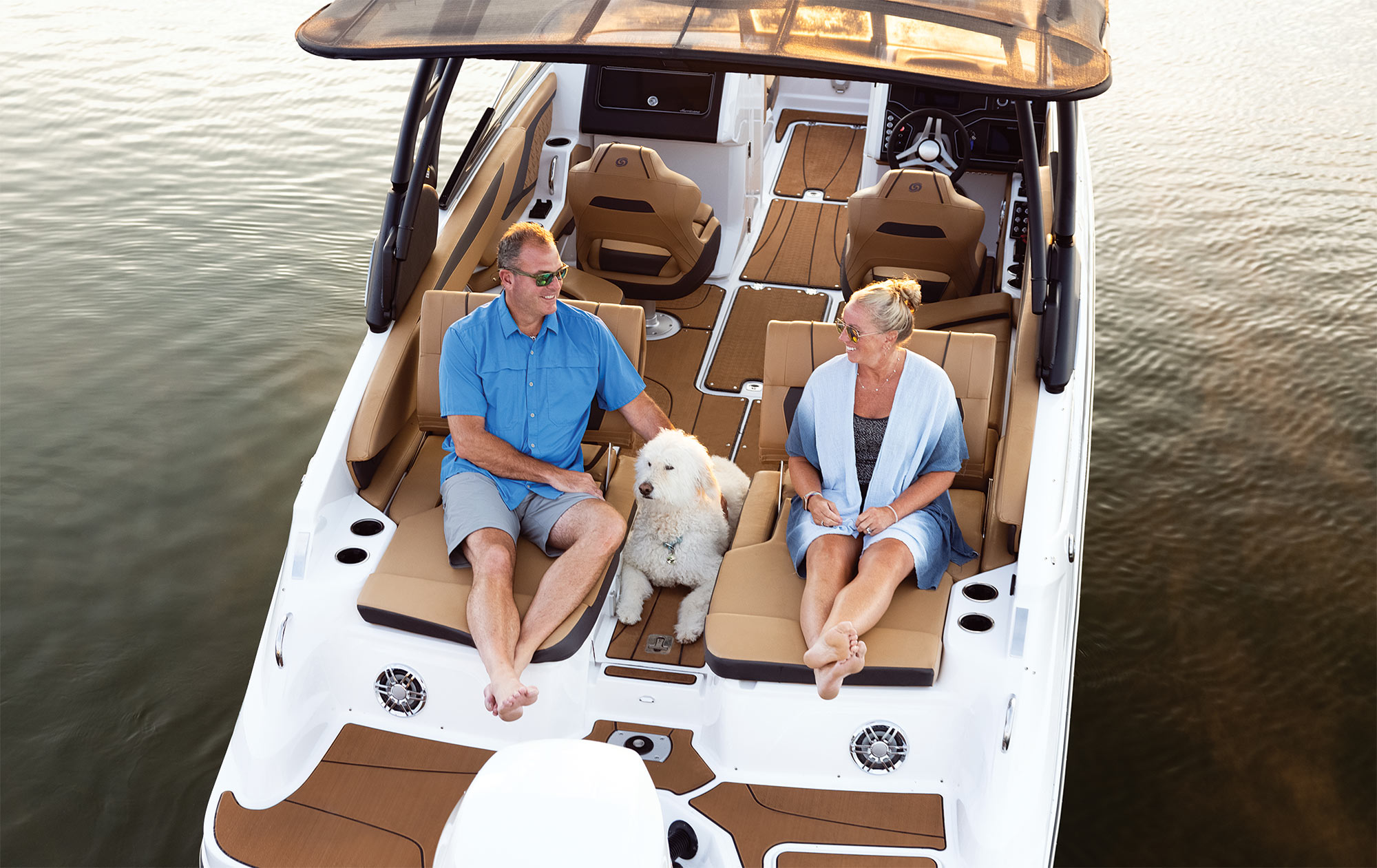 man, woman, and dog sitting on front of boat smiling
