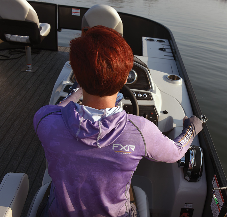 woman's back as she's in the drivers seat of a boat