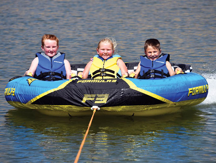 Three kids riding on the HO Sports Formula 3 towable