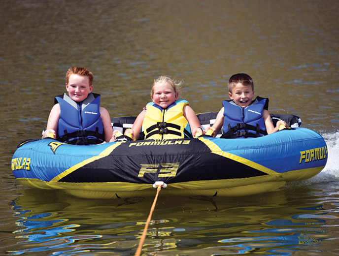 Three kids riding on the HO Sports Formula 3 towable