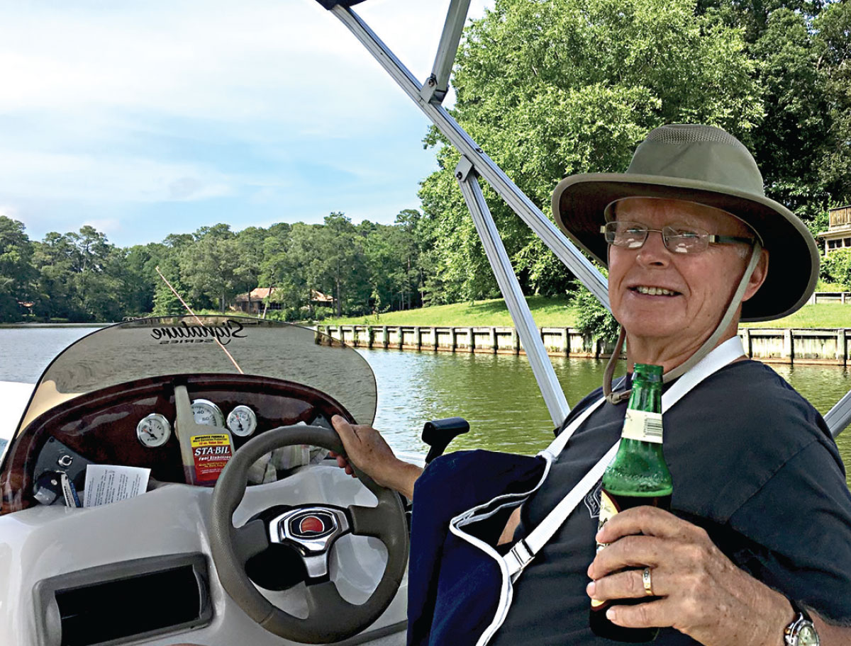 Robert E. Rumney on boat with a glass bottle smiling