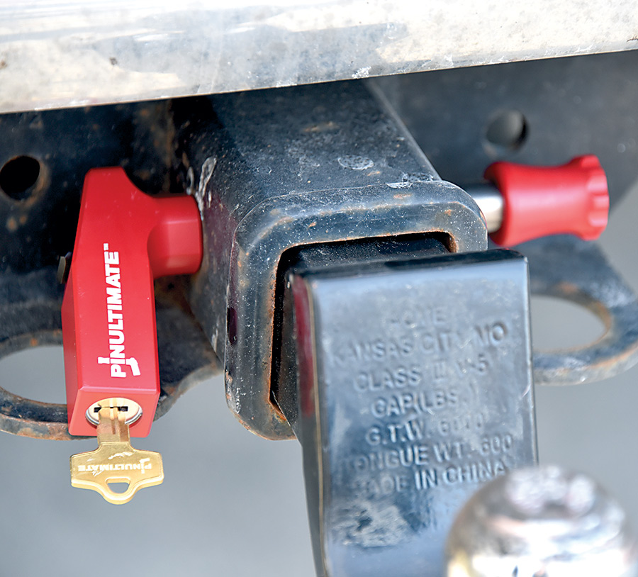 Close-up photograph perspective of the new all-titanium PinUltimate Quick-Release Hitch Pin with a key inserted into the product while being secured onto the tow hitch