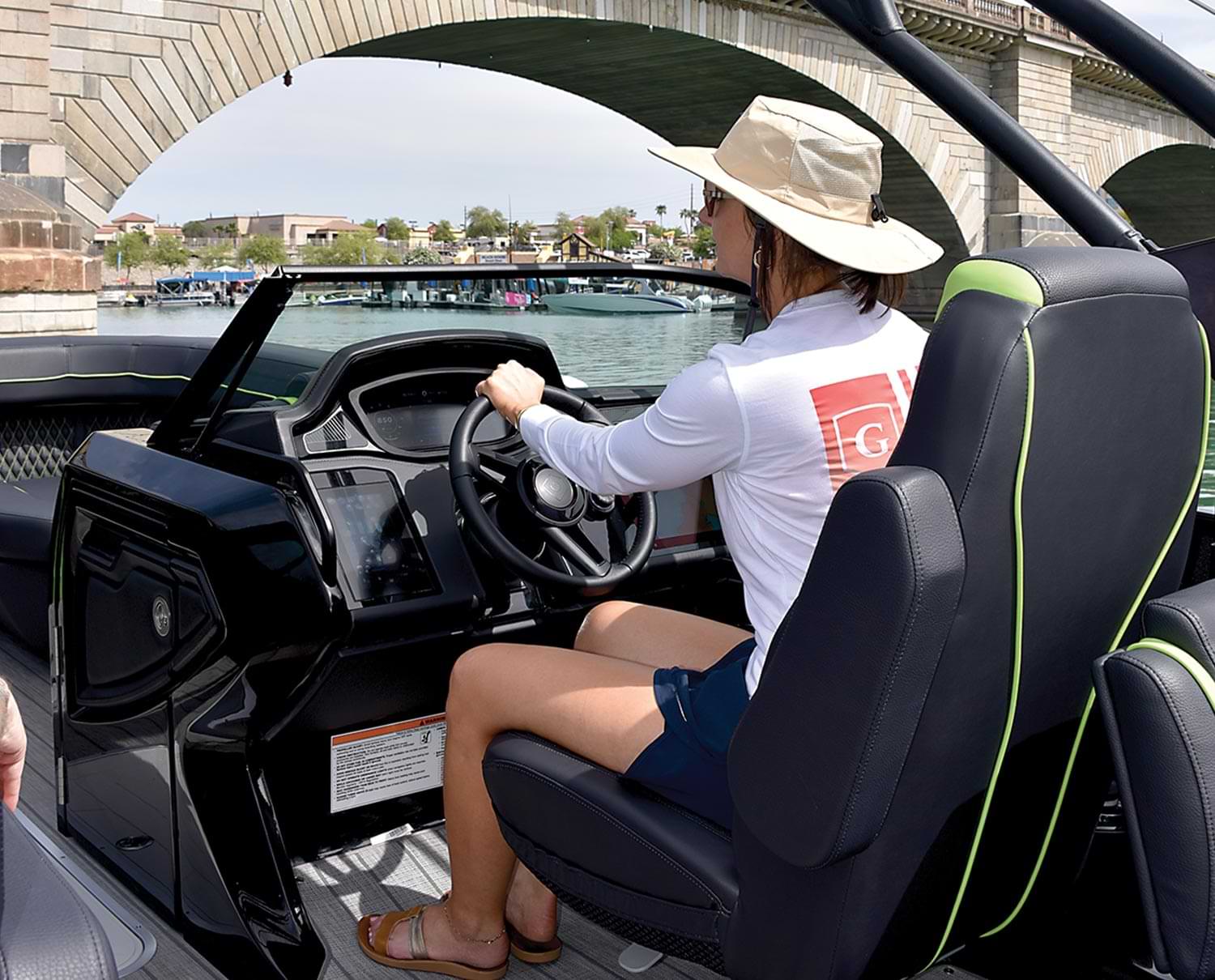 3/4ths back view of a woman steering a Godfrey XP series pontoon while in the captain's chair