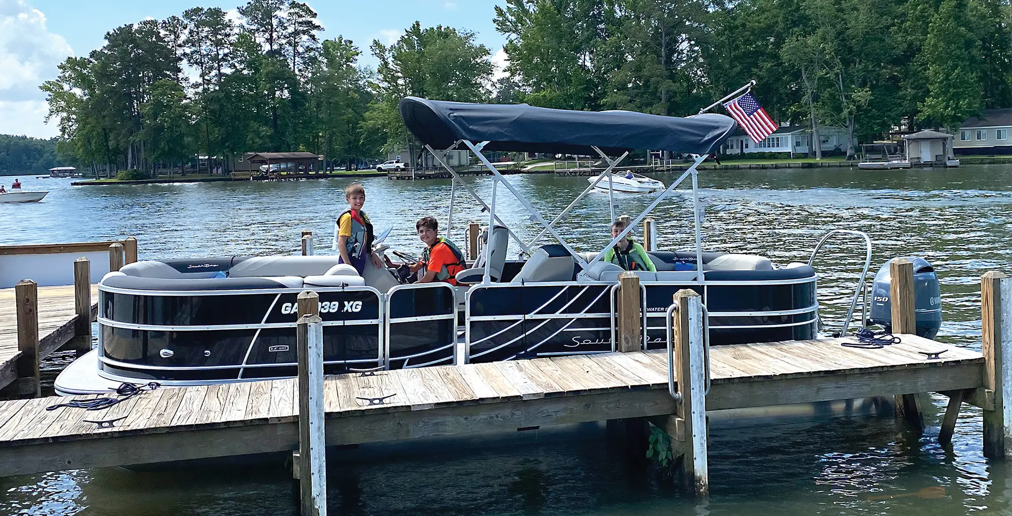 3 boys smile for a photo on the pontoon