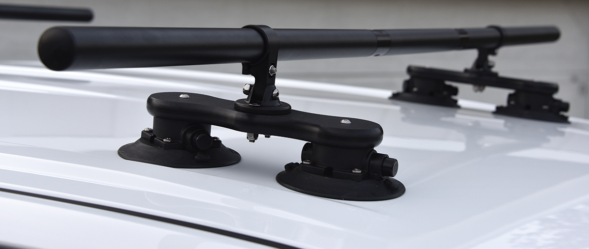 Close-up angle photograph of a SeaSucker Monkey Bar crossbar roof rack system installed on top of a white truck