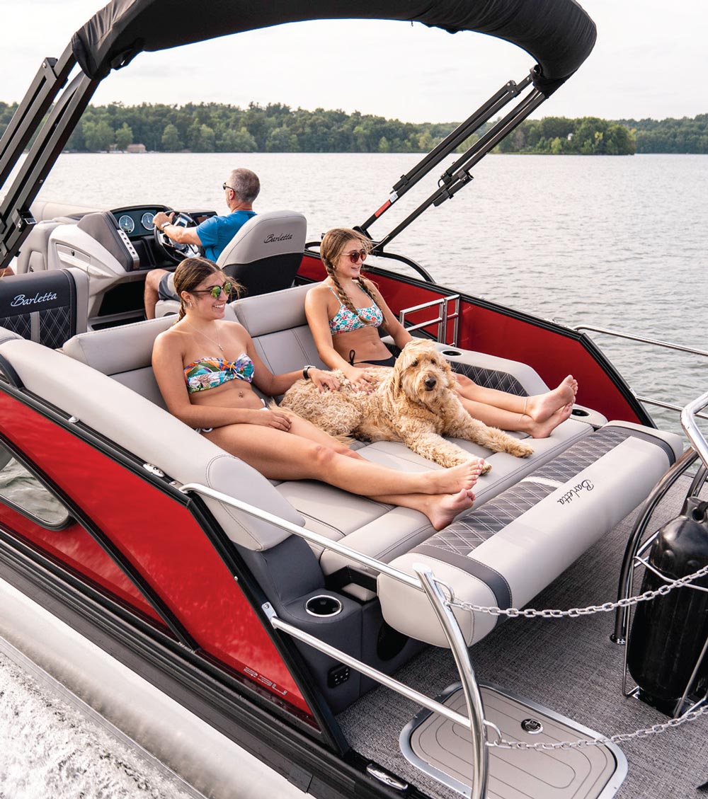 dad driving a boat with his two daughters and their dog sitting on the backside