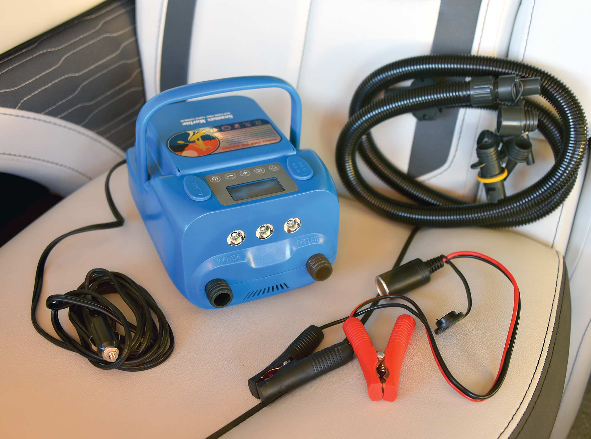 Close-up photograph perspective of the blue colored Seamax Marine SUP16DB Electric Air Pump and other assorted black and red colored cable accessories