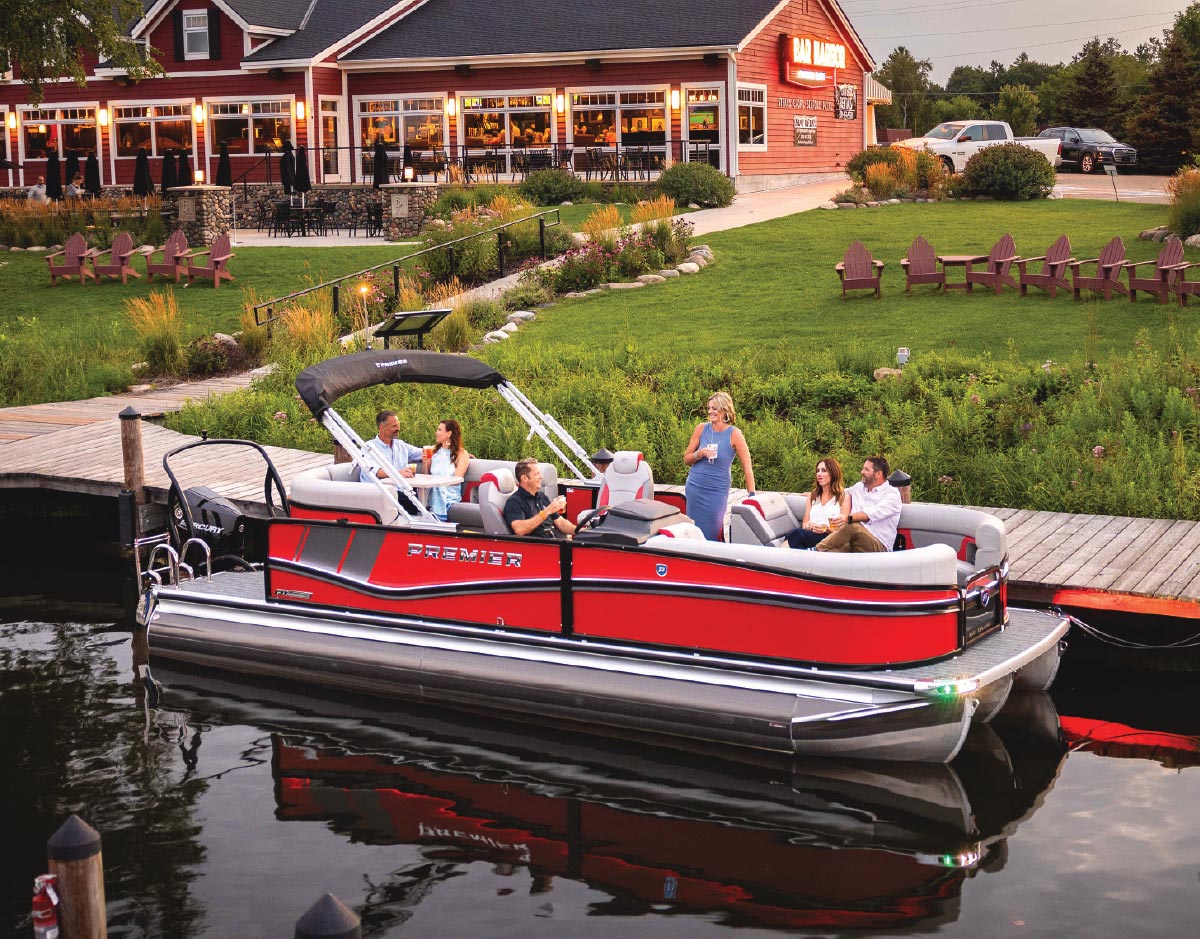 red premier boat docked by restaurant full of men and women