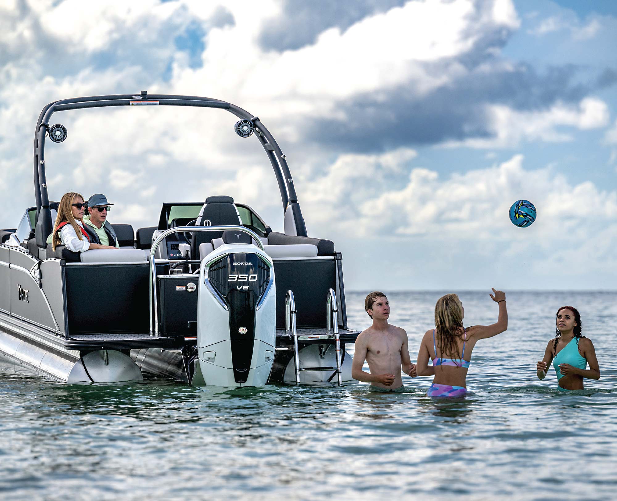 man and woman on boat watching boy and two girls throwing ball in water