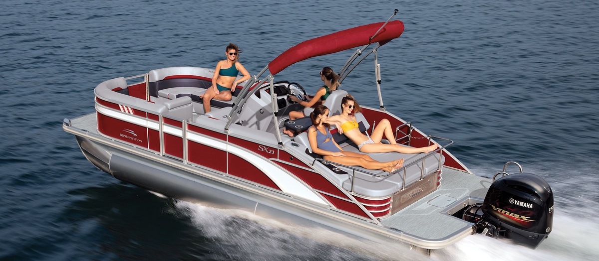 Four women riding in a grey and red Bennington pontoon on the water.