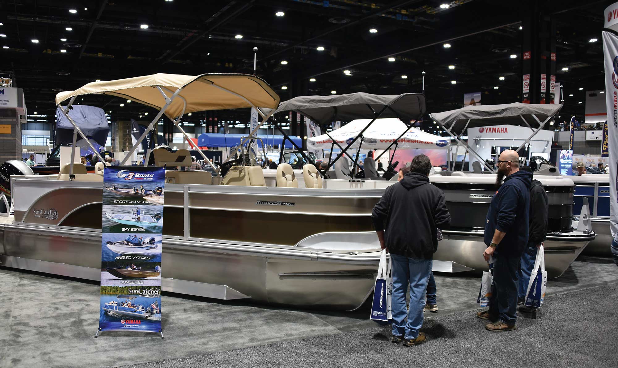 three men looking at tan boat in show room