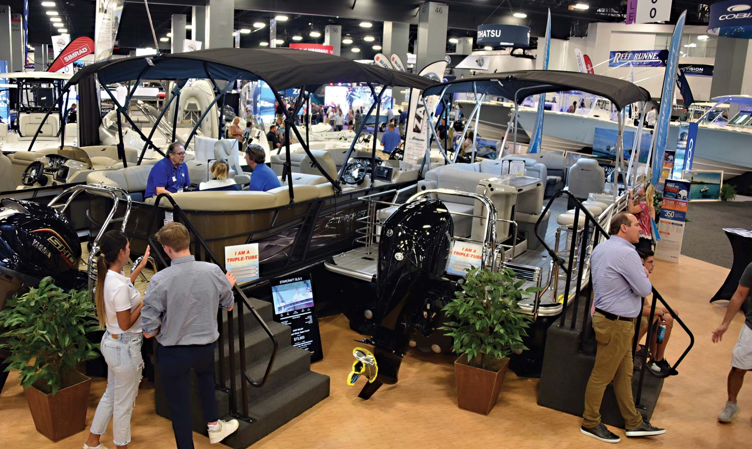 crowd hanging out by stairs leading up to boats in showroom