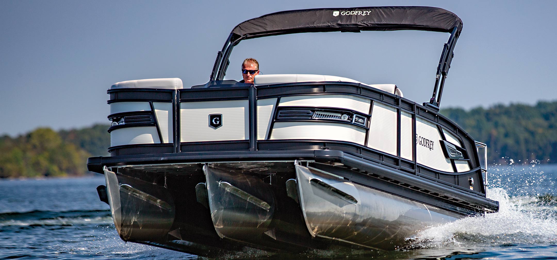 Man driving a black and white Godfrey Pontoon boat