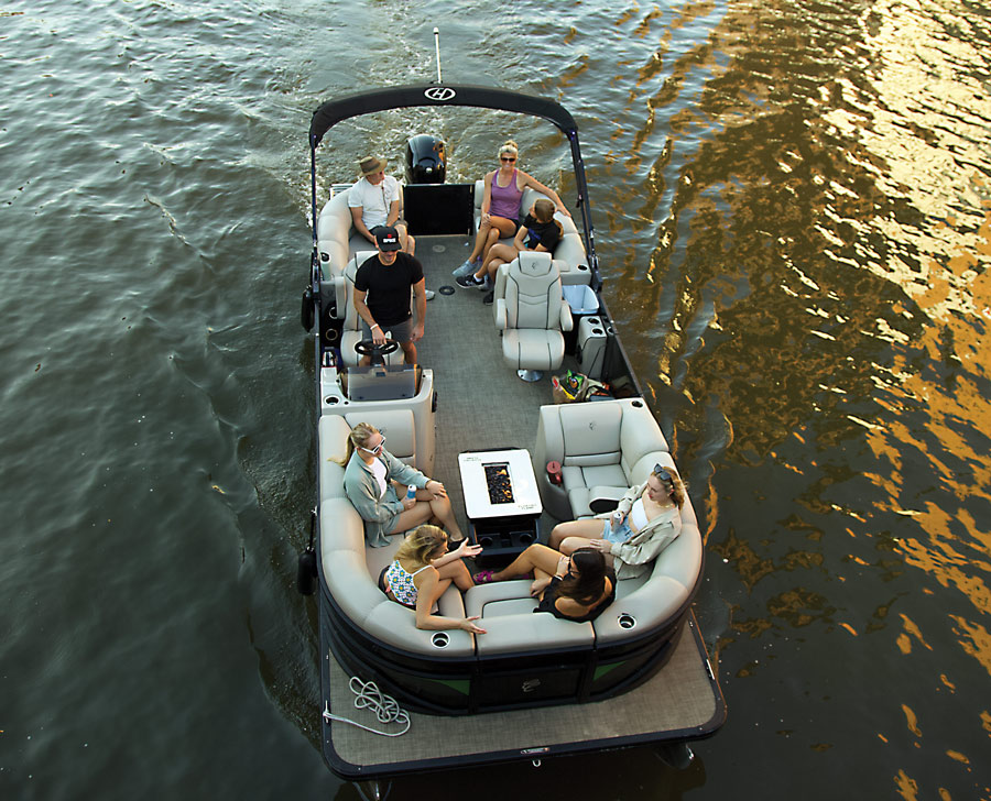 aerial shot of a pontoon with four women sitting together around a fire pit