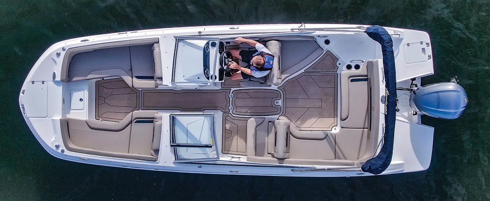 Aerial angle side photo view of the Hurricane SunDeck 235 pontoon motorboat vehicle as a man is seen driving the pontoon out in the water
