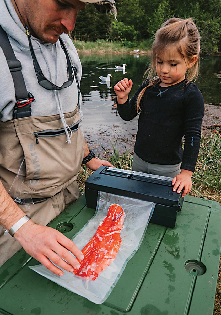 a man and a young girl use the Vacuum Sealer from PacBak to preserve a Salmon fillet