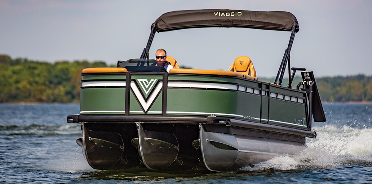 port side quarter view of a man wearing sunglasses operating a green Viaggio Lago X24S on an enclosed body of water