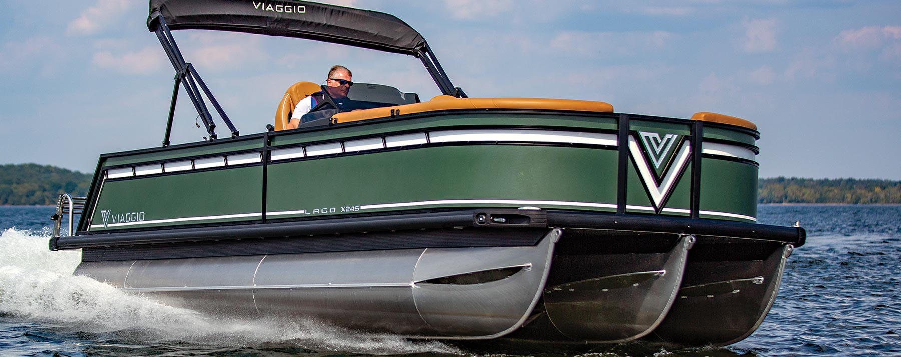 starboard side view of a man wearing sunglasses operating a green Viaggio Lago X24S on an enclosed body of water