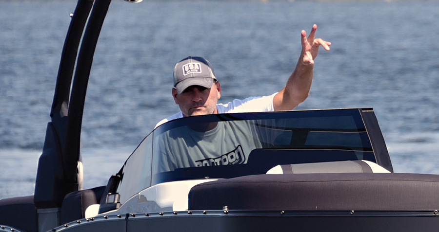 Keith Nicolini driving boat with peace sign in air