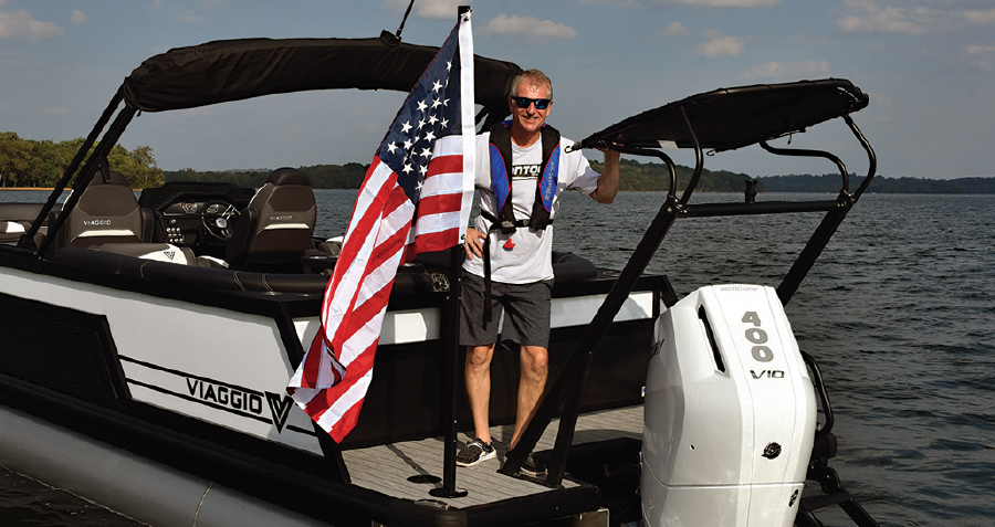 Corey Schaub on rear of boat holding American flag