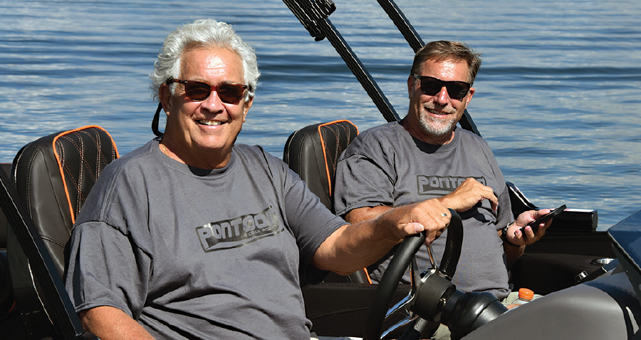 Randy “Cotton” O’Malia and Clayton Ward smiling while driving boat