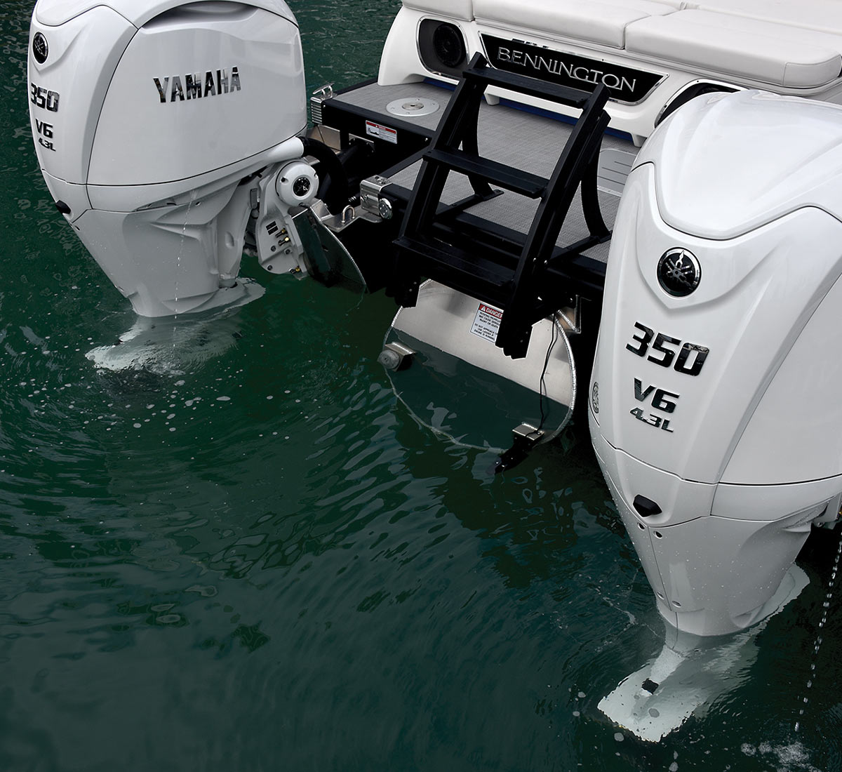 zoomed in view of twin F350 outboards in white at the stern of a Bennington pontoon in water