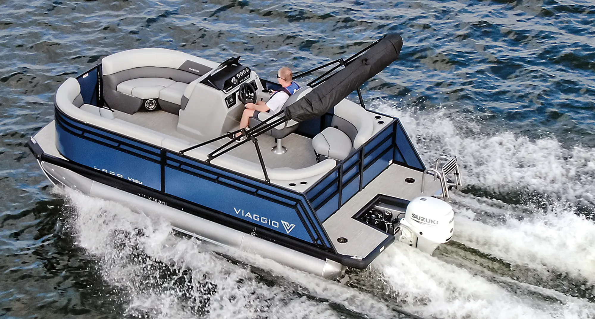 Landscape aerial top angle photograph view of a man in a t-shirt and sunglasses in the driver's seat driving the Viaggio Lago V16U pontoon motorboat vehicle out in the water