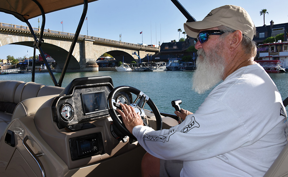 man driving a boat in Lake Havasu with the London Bridge in the background