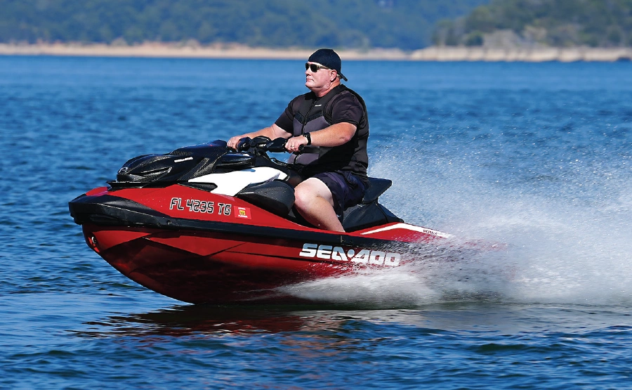 man riding red sea-doo with black and red accents on water