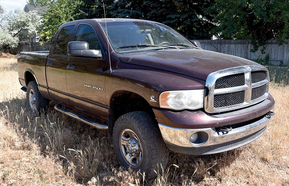 Landscape photograph angle view of a dark burgundy colored 2004 Dodge RAM 2500 5.9L Cummins truck vehicle parked somewhere outside on some tan colored dead grass in a neighborhood area