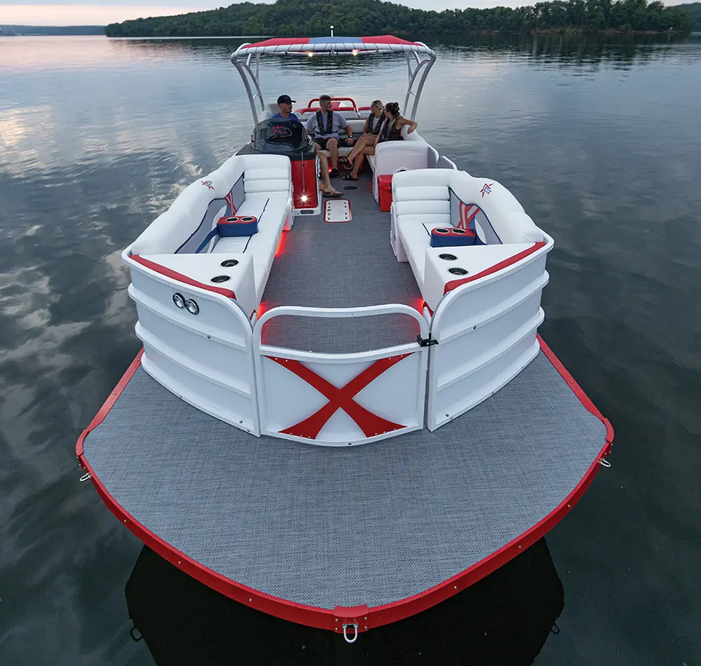 front high angle shot of a red and white Legacy Edition Playcraft Powertoon X-Treme, two couples relax on the pontoons rear bench near the helm