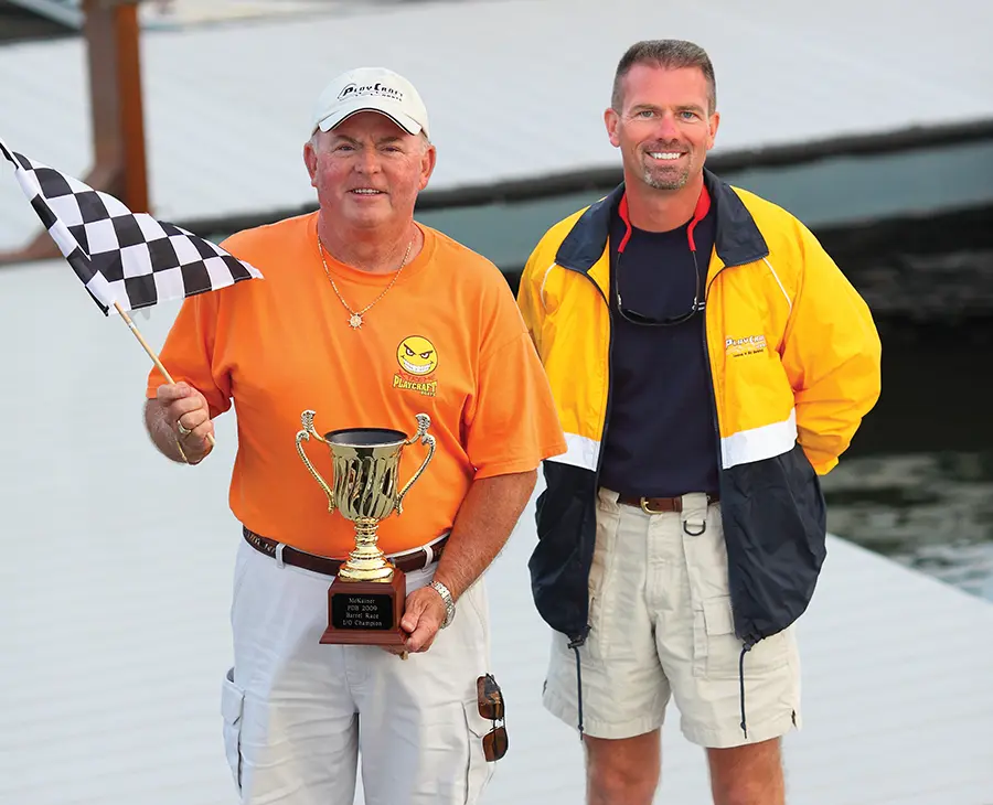 Jim Dorris photographed holding a trophy and a mini finish line flag and standing beside his son Joe Dorris