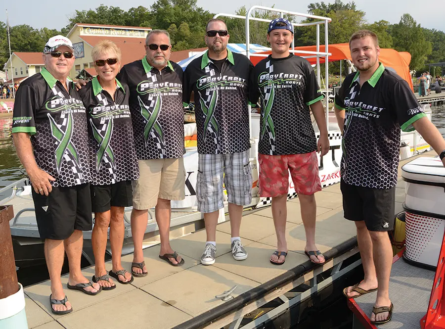 Jim Dorris photographed with his family and employees, all wearing black, white and green Playcraft Boats branded shirts