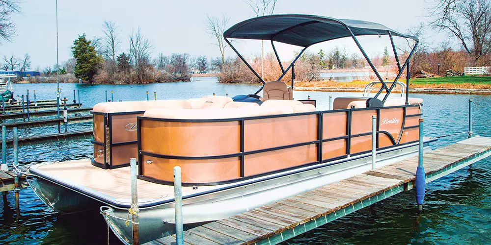 quarter view of a pontoon with an Eclipse Powered Bimini installed docked beside a small pier