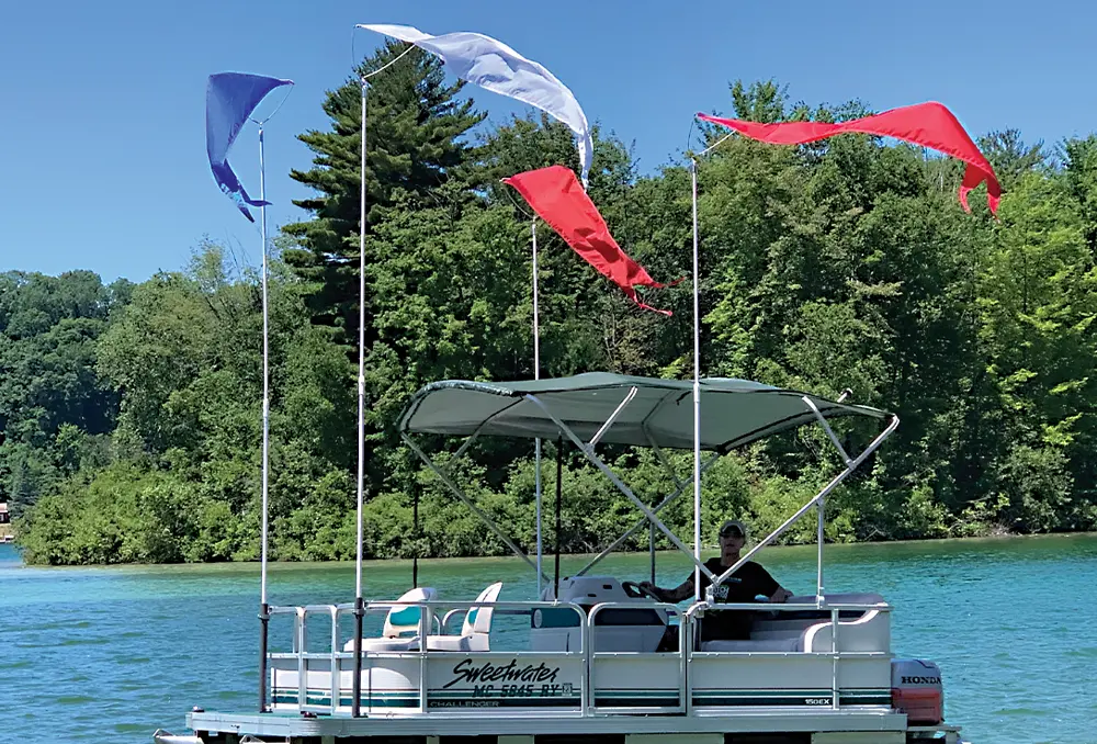 four nylon pennants, in the colors blue, white, and red, sway from atop poles installed on a floating pontoon