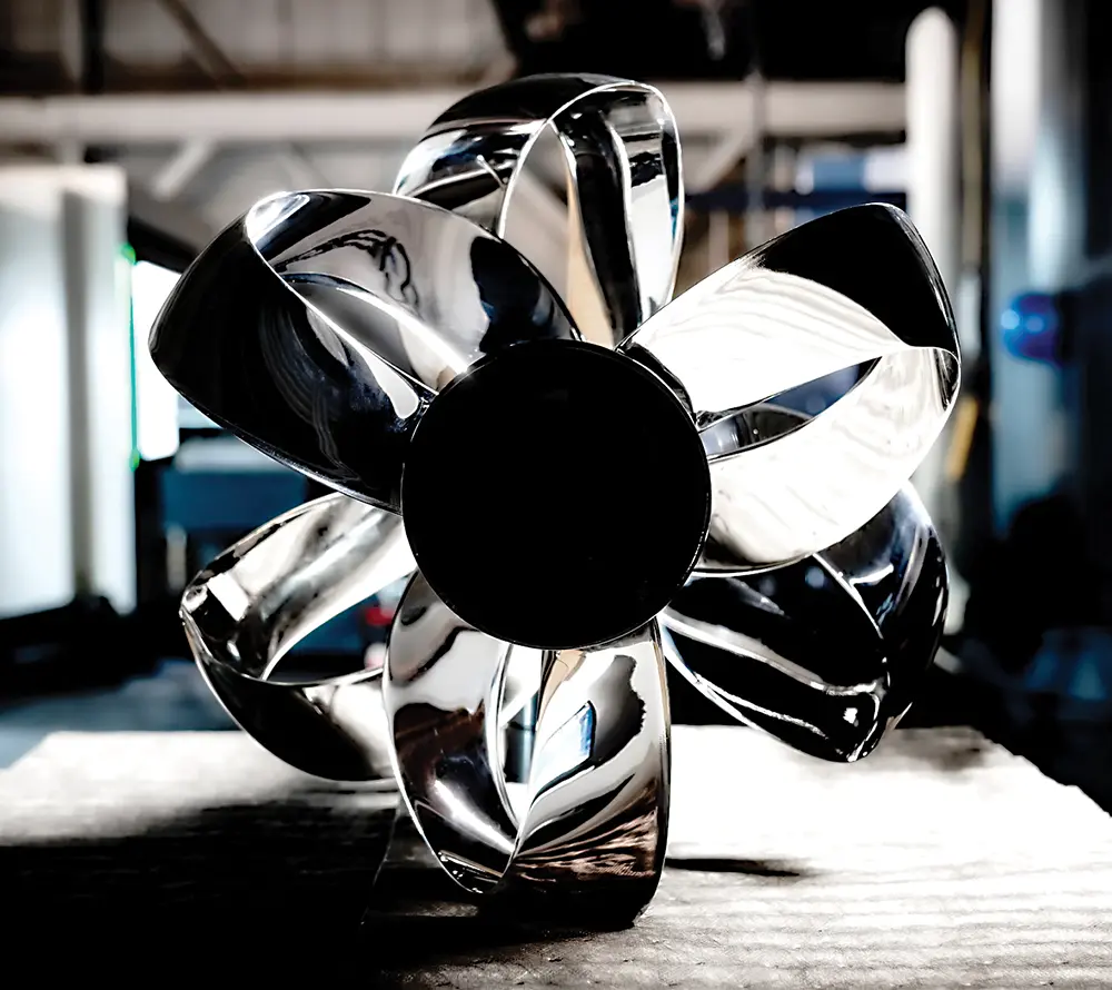 a stainless steel Sharrow Marine propeller placed on a wooden surface