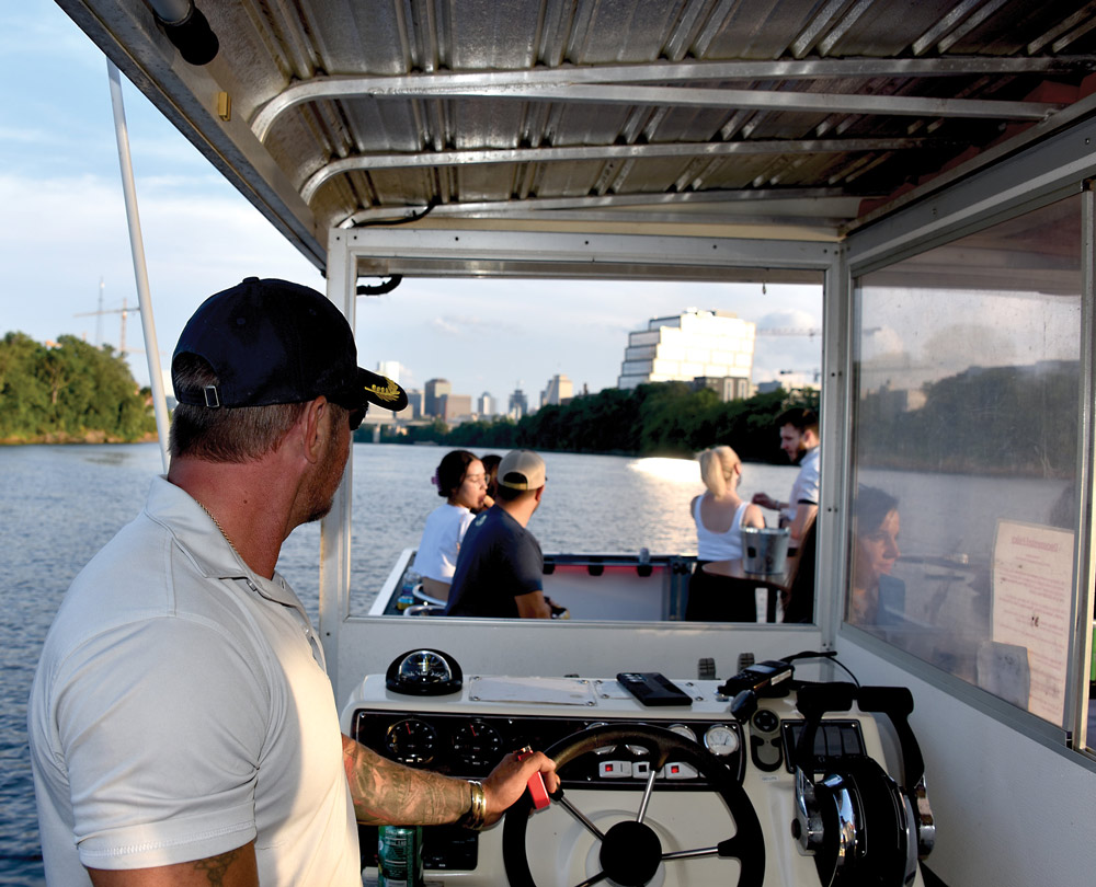 man driving a boat with other people hanging out in the front