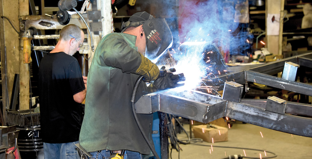 two men wearing safety goggles and a welding mask welding metal together