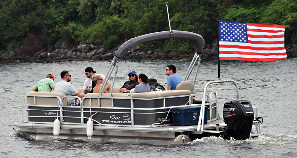 pontoon boat with a group of people and an American flag waving from the back