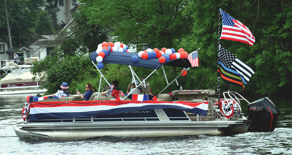 pontoon boat covered with red, white, and blue balloons and American flags