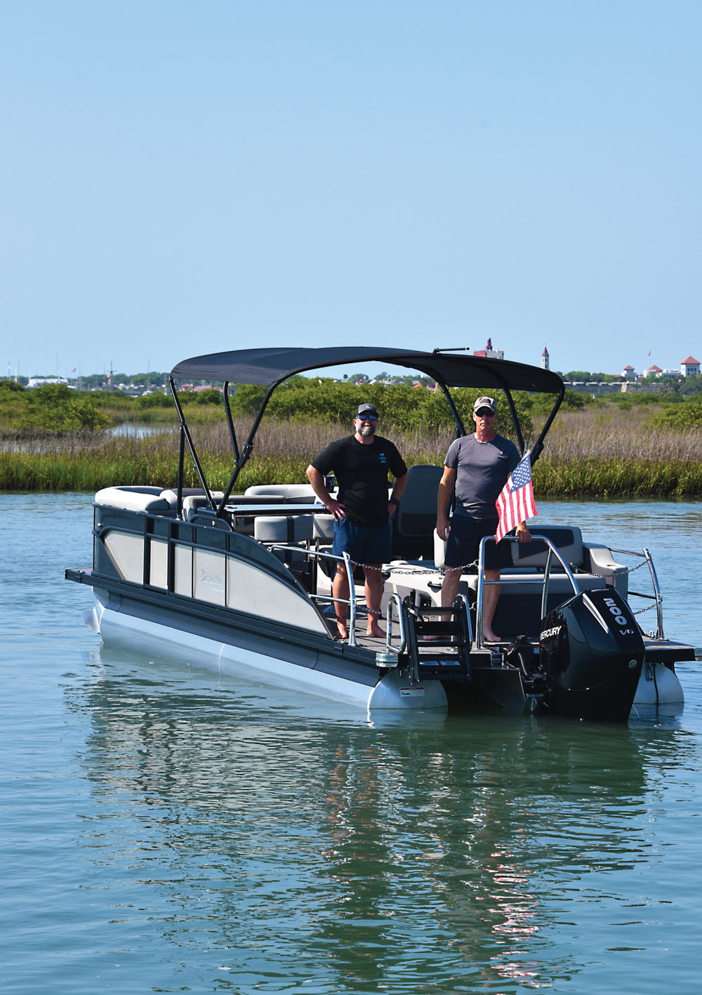 two men standing next to an American flag on their boat