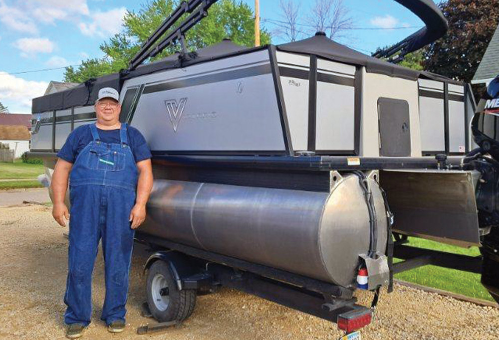 man standing next to a boat parked on land