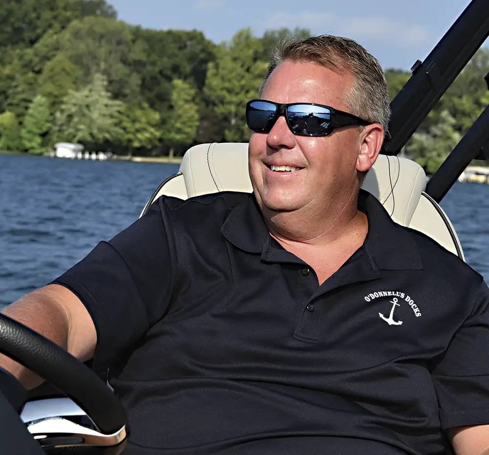 Shawn O'Donnell wearing sunglasses and smiling while at the helm of his Barletta pontoon