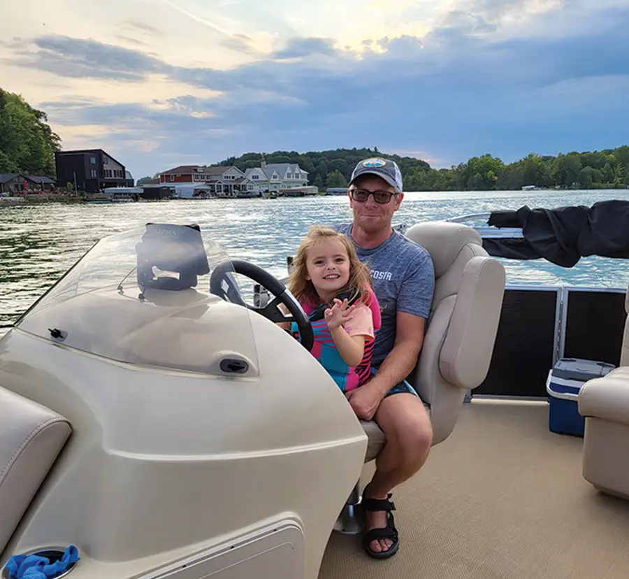 dad and daughter sitting at the captain's chair of a pontoon